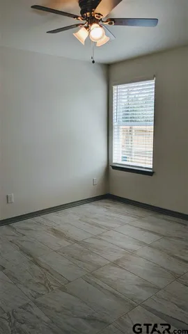 an empty room with a chandelier fan and windows