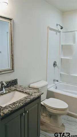 a bathroom with a granite countertop toilet a sink and a mirror