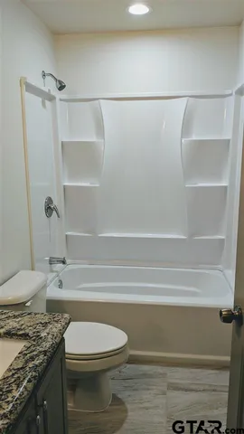 a bathroom with a granite countertop bathtub sink vanity and toilet