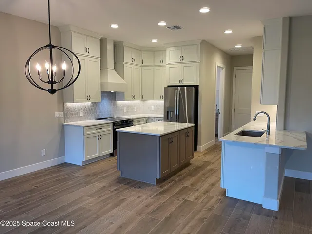a kitchen with stainless steel appliances granite countertop a sink a stove and a wooden floors