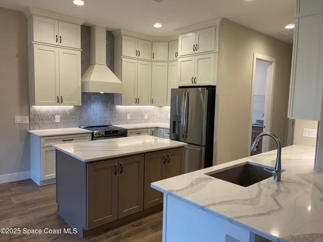 a kitchen with stainless steel appliances a sink a refrigerator and wooden cabinets
