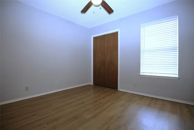 an empty room with ceiling fan and window