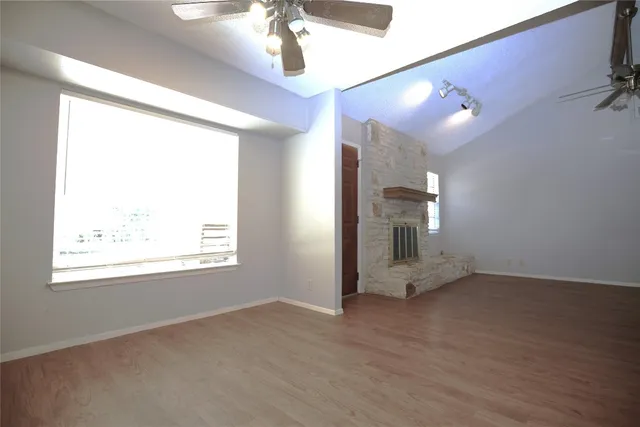 an empty room with chandelier fan and windows