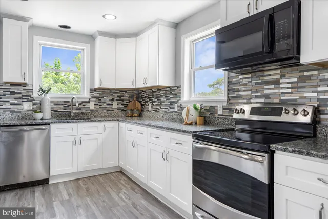 a kitchen with stainless steel appliances white cabinets granite counter tops and a hard wood floors