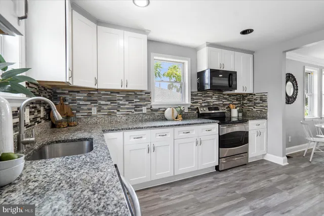 a kitchen with stainless steel appliances granite countertop a stove a sink and a microwave