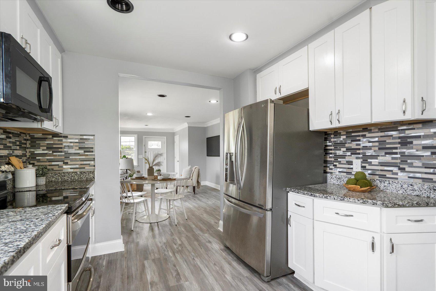 6628 Hartwait Street Baltimore, MD 21224 - Photo 8 of 31 a kitchen with stainless steel appliances a refrigerator stove microwave and cabinets