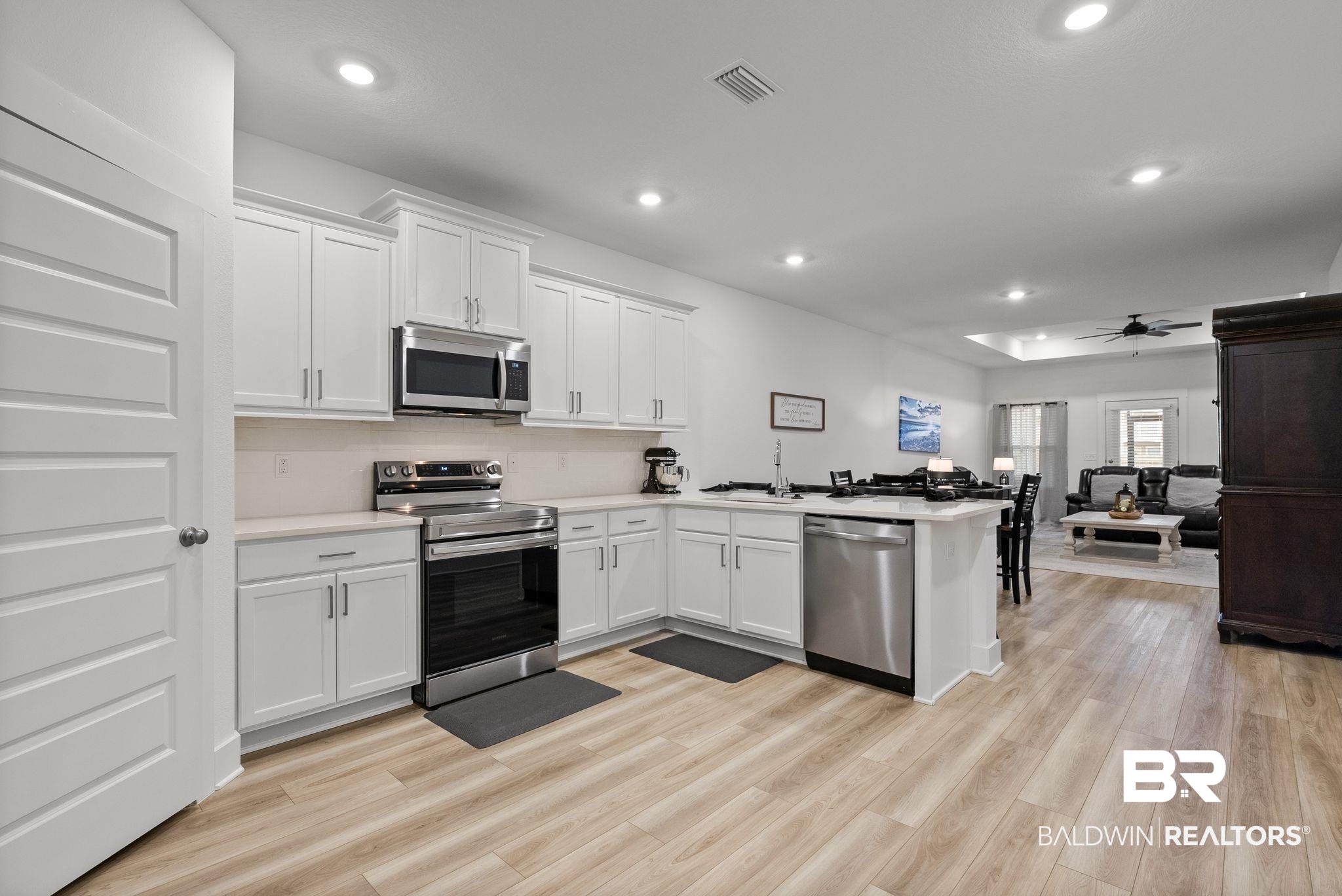 9899 Willet Way Foley, AL 36535 - Photo 11 of 37 Kitchen featuring white shaker cabinetry, stainless steel appliances, light-toned countertops, and wood-finish flooring