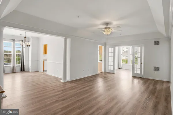 a view of an empty room with window and wooden floor