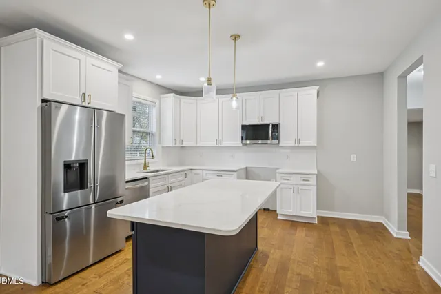 a kitchen with kitchen island a counter top space stainless steel appliances and cabinets