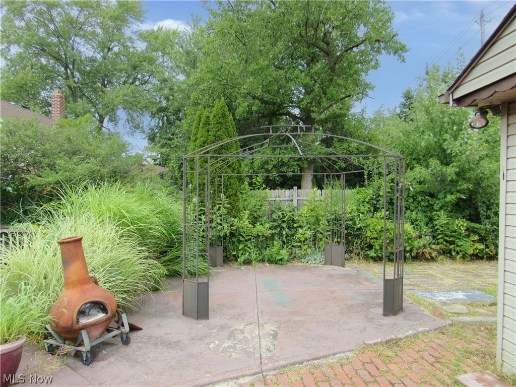 4067 East 187th Street Cleveland, OH 44122 - Photo 21 of 26 Patio space featuring concrete and brick paving, a garden arch structure, and surrounding mature landscaping