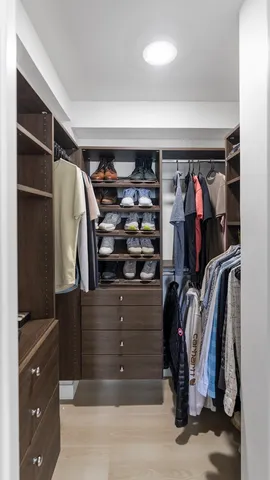 a view of walk in closet with clothes and shoes