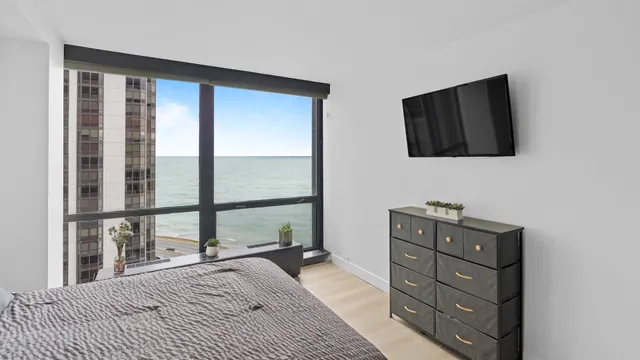 a bedroom with a bed and a flat tv screen on dresser