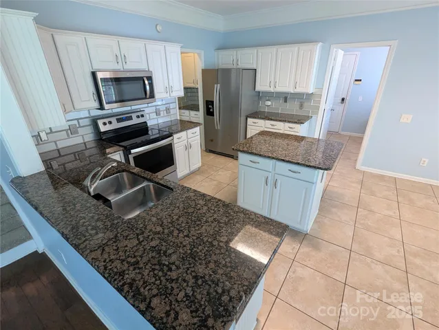 a kitchen with stainless steel appliances granite countertop a sink stove microwave and refrigerator
