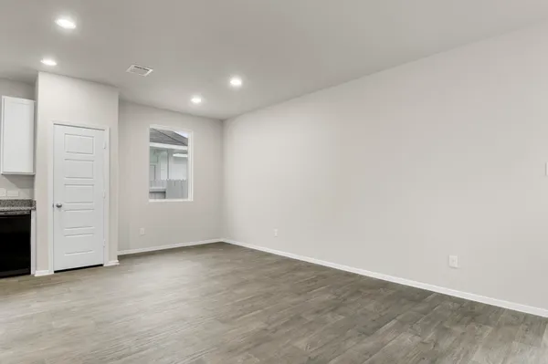 an empty room with wooden floor & window and bathroom
