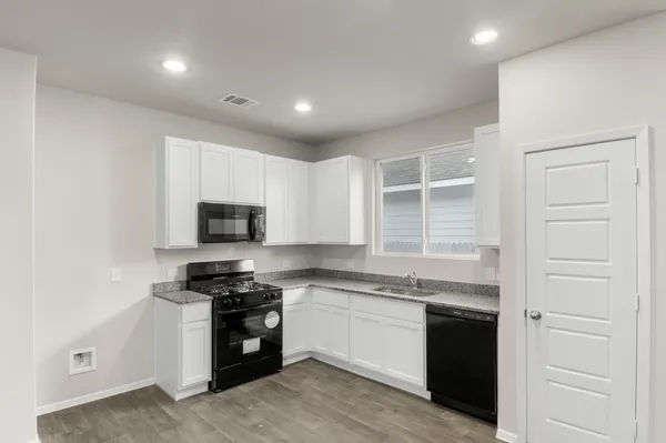 a kitchen with stainless steel appliances granite countertop a stove a sink and a microwave