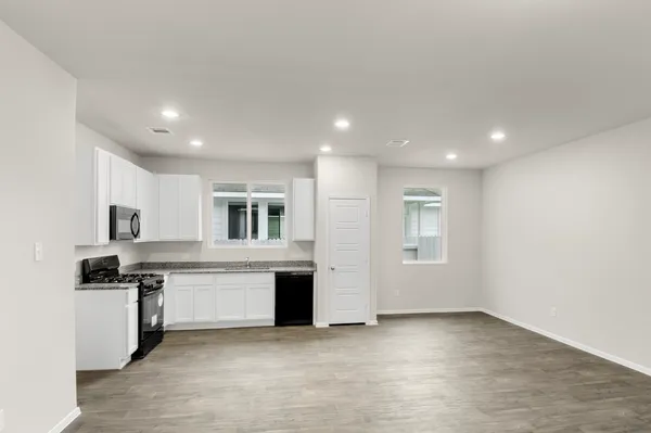 a kitchen that has a lot of cabinets in it and wooden floors
