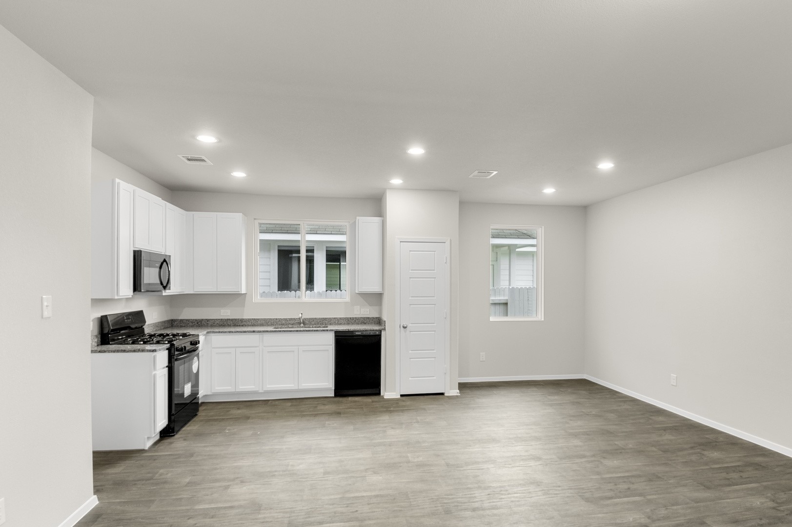 3043 Winding Creek Road Kyle, TX 78640 - Photo 18 of 30 an empty room with kitchen view and wooden floor