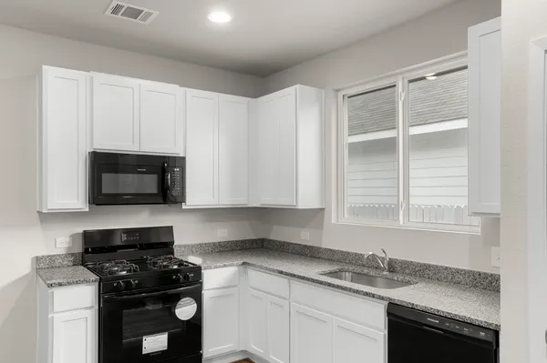 a kitchen with granite countertop white cabinets and black appliances