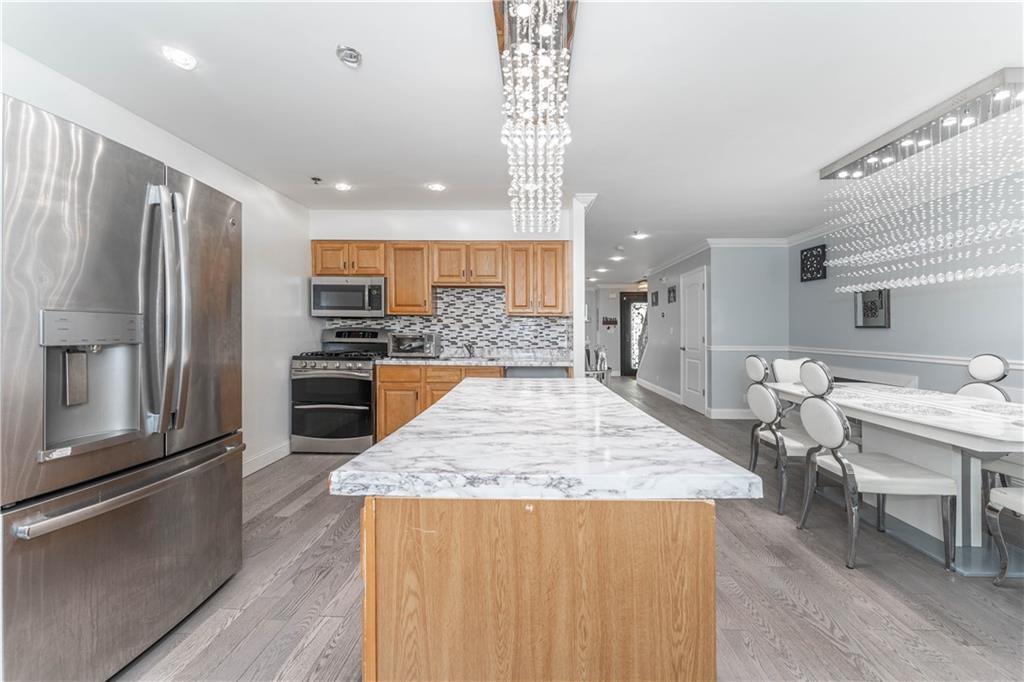 724 Egan Street Brooklyn, NY 11239 - Photo 10 of 10 a kitchen with stainless steel appliances granite countertop a refrigerator oven a sink dishwasher and a dining table with wooden floor