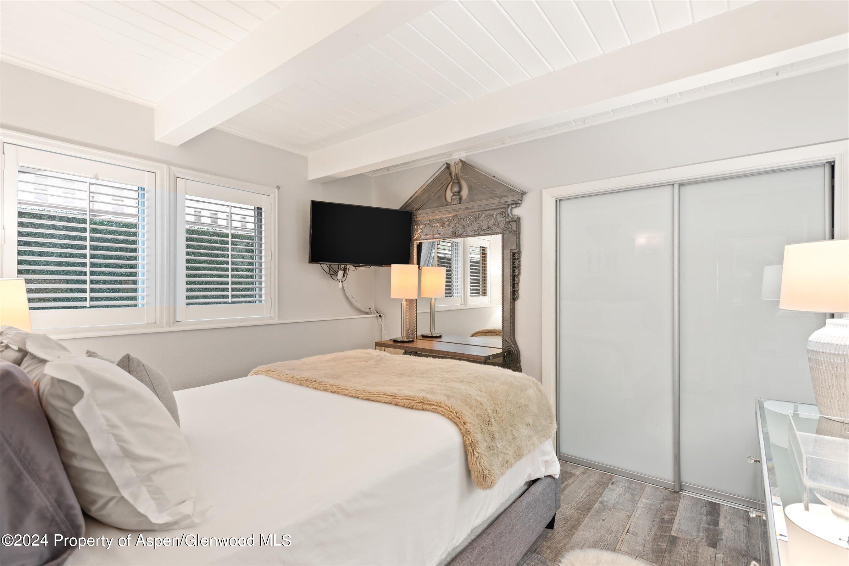 825 East Hopkins Avenue, Unit 1N Aspen, CO 81611 - Photo 7 of 16 a bedroom with a large bed and a flat tv screen on dresser