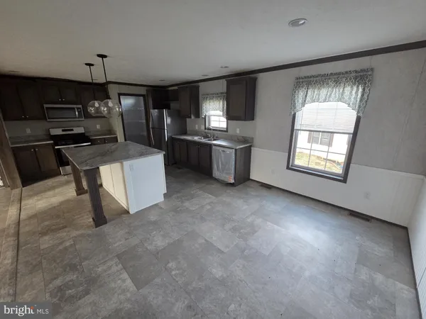 a living room with couches and kitchen view with wooden floor