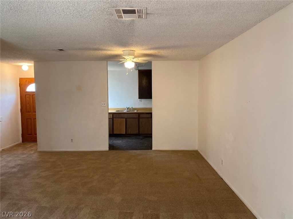 6433 Addely Drive Las Vegas, NV 89108 - Photo 11 of 27 Empty room featuring carpet floors, ceiling fan, and a textured ceiling