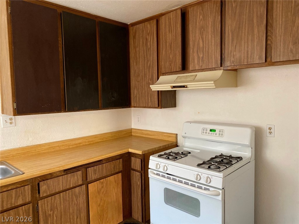 6433 Addely Drive Las Vegas, NV 89108 - Photo 15 of 27 Kitchen with white gas range, light countertops, and wood finish cabinets