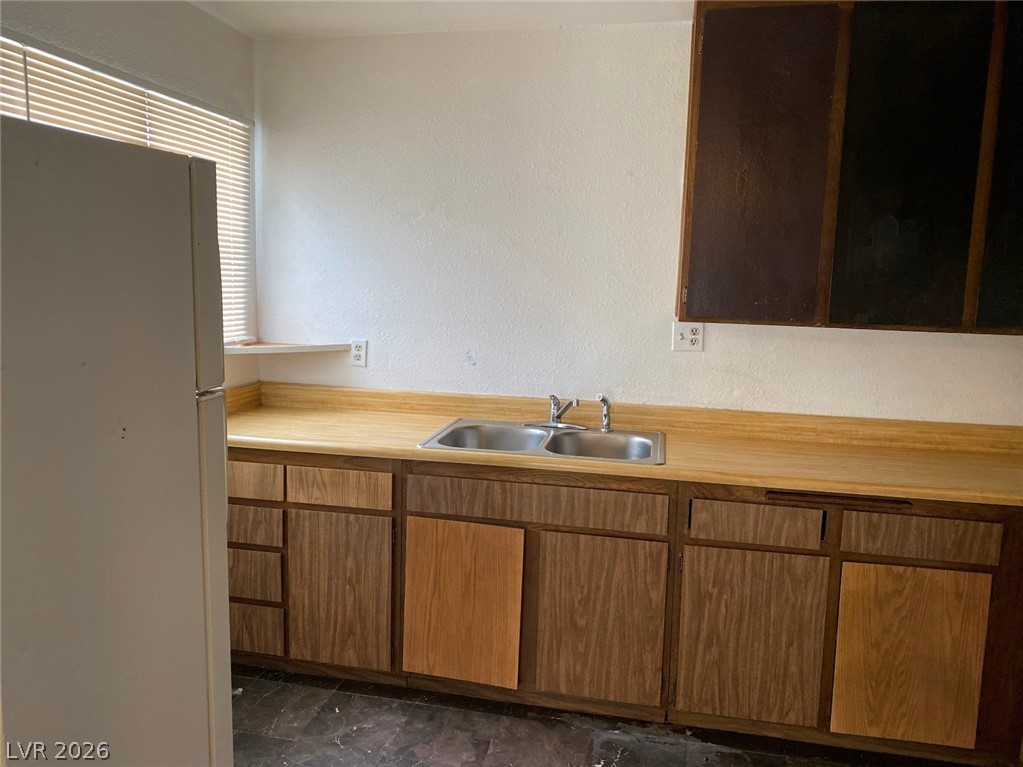 6433 Addely Drive Las Vegas, NV 89108 - Photo 16 of 27 Kitchen with freestanding refrigerator, a textured wall, and light countertops