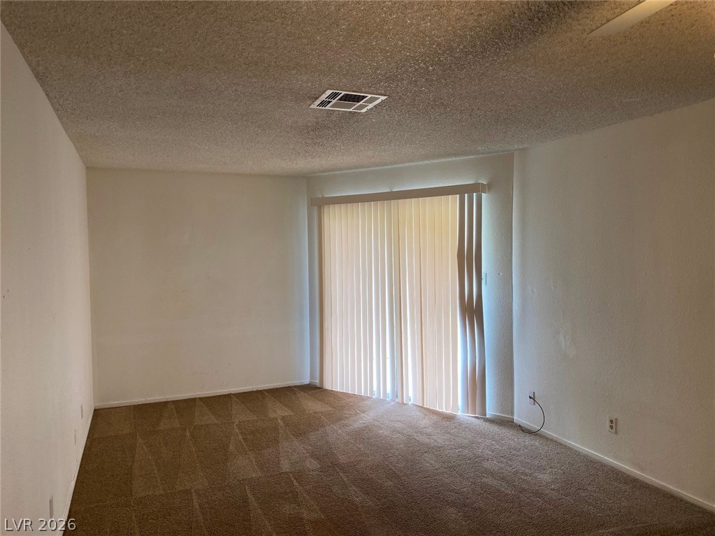 6433 Addely Drive Las Vegas, NV 89108 - Photo 6 of 27 Unfurnished room featuring dark colored carpet and a textured ceiling