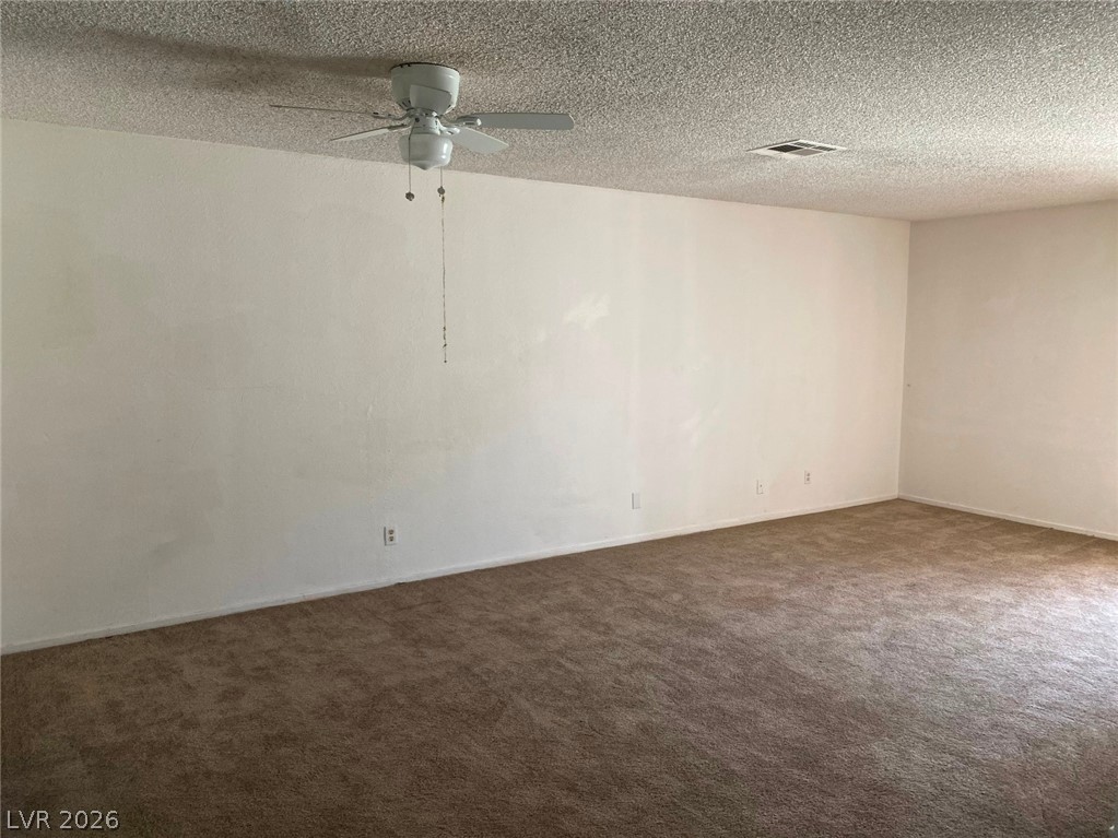 6433 Addely Drive Las Vegas, NV 89108 - Photo 8 of 27 Unfurnished room featuring a textured ceiling, ceiling fan, and dark carpet