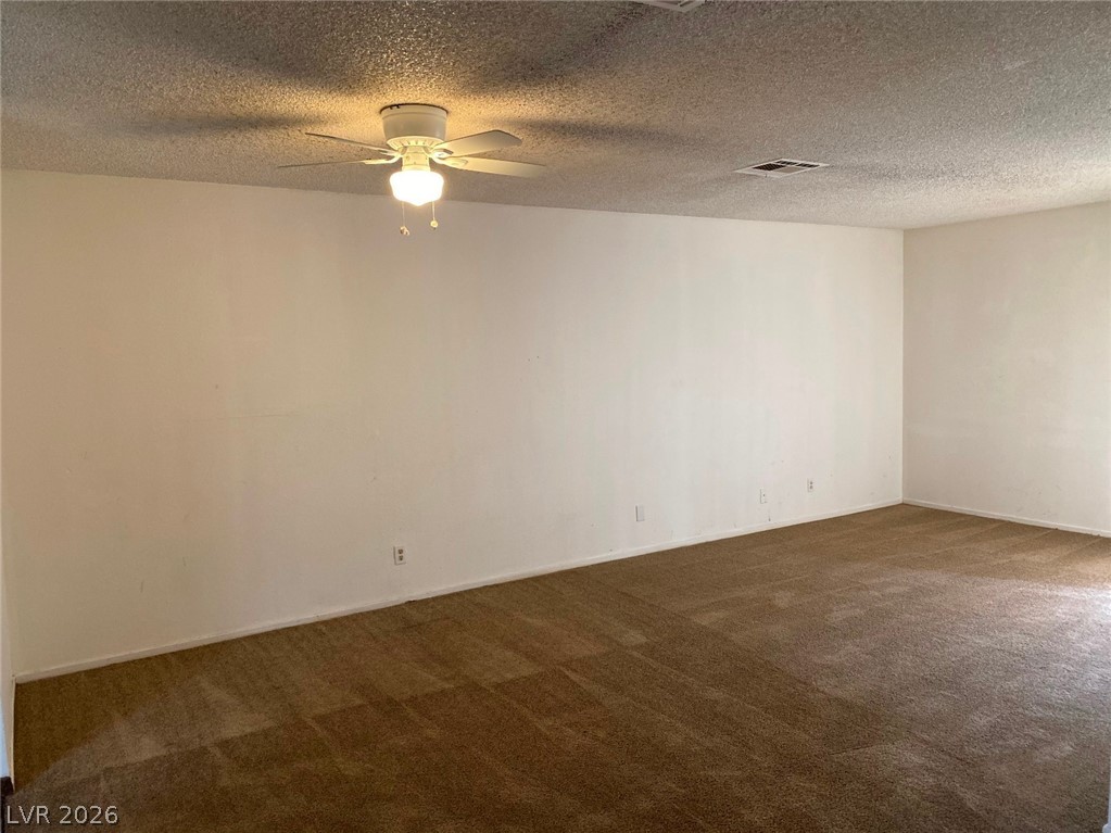 6433 Addely Drive Las Vegas, NV 89108 - Photo 9 of 27 Unfurnished room with dark carpet, a ceiling fan, and a textured ceiling
