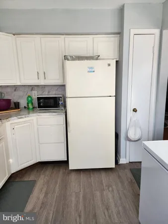a kitchen with a refrigerator and white cabinets