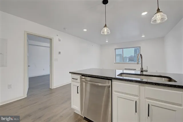 a kitchen with a sink chandelier and wooden floor