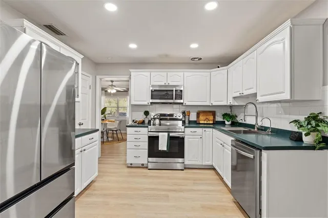 a kitchen with stainless steel appliances granite countertop a refrigerator a stove top oven a sink and dishwasher