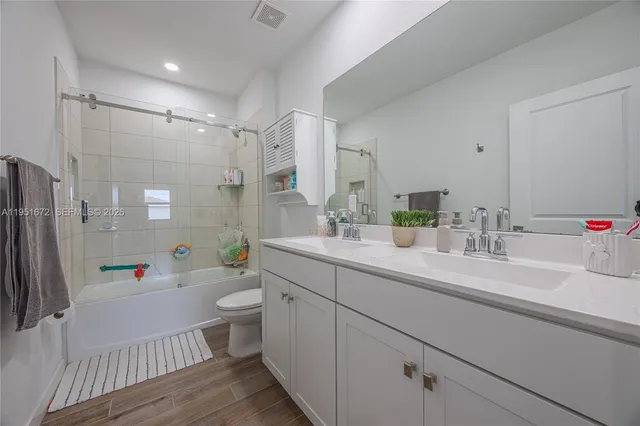 a bathroom with a sink a toilet a mirror and shower