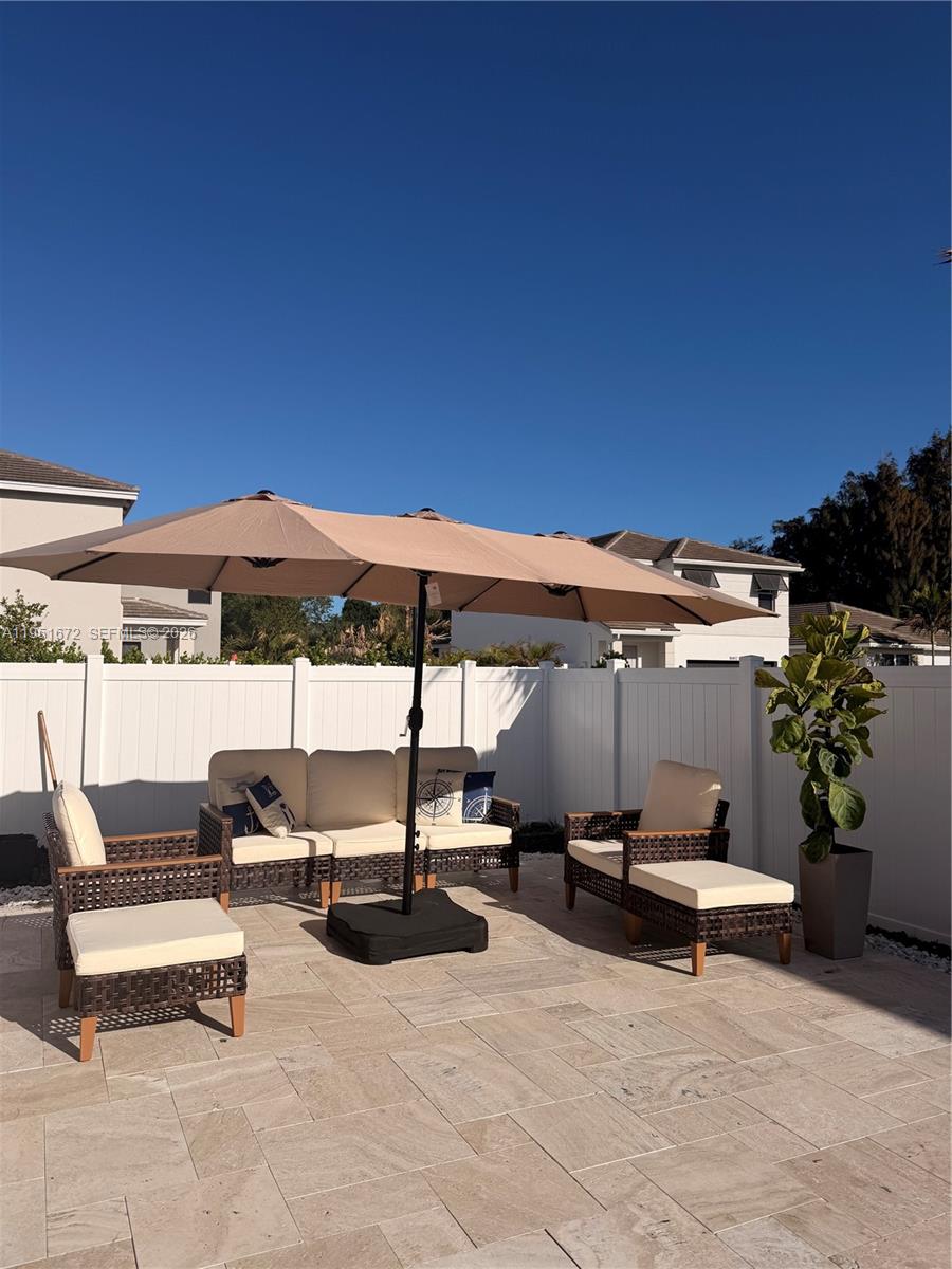 7126 Rockwood Road Jupiter, FL 33458 - Photo 7 of 35 a view of a patio with a table and chairs under an umbrella with a fire pit