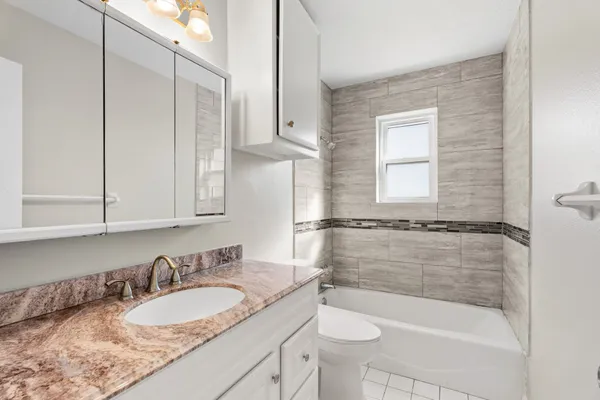 a bathroom with a granite countertop sink a toilet and bathtub