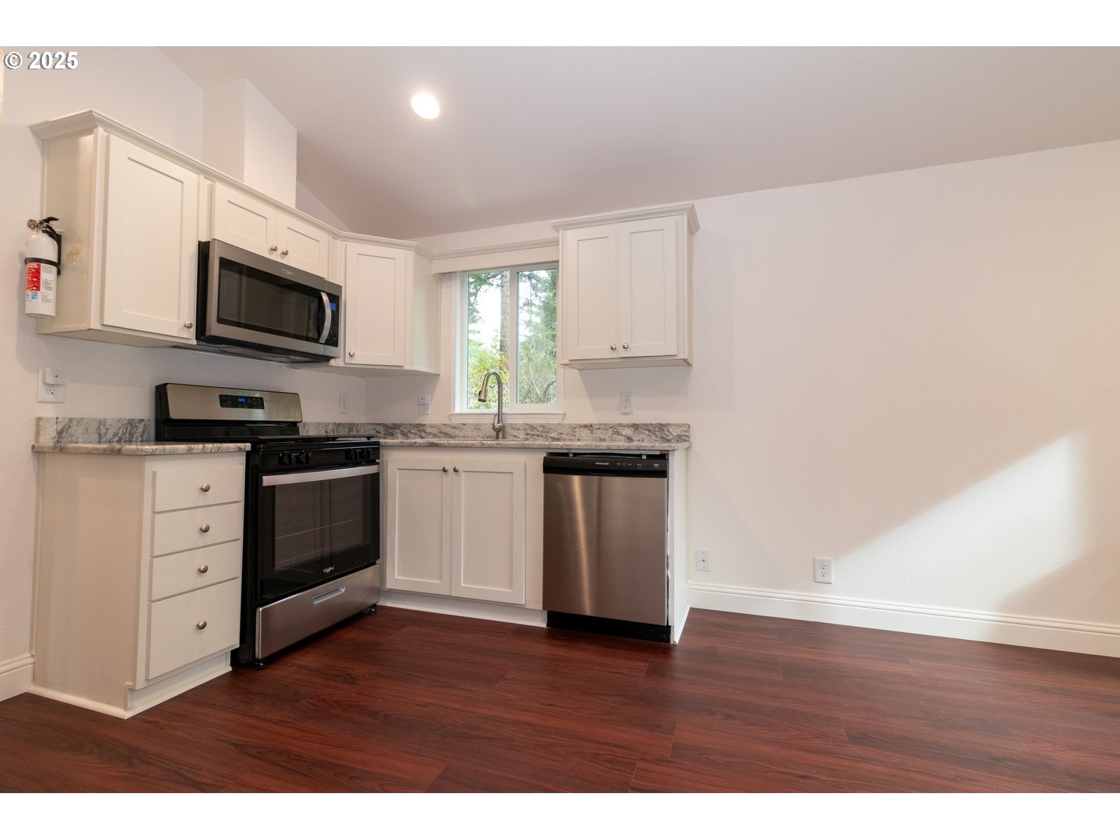 231 Horseshoe Bend Florence, OR 97439 - Photo 8 of 26 a kitchen with stainless steel appliances white cabinets a sink a stove a microwave and wooden floors