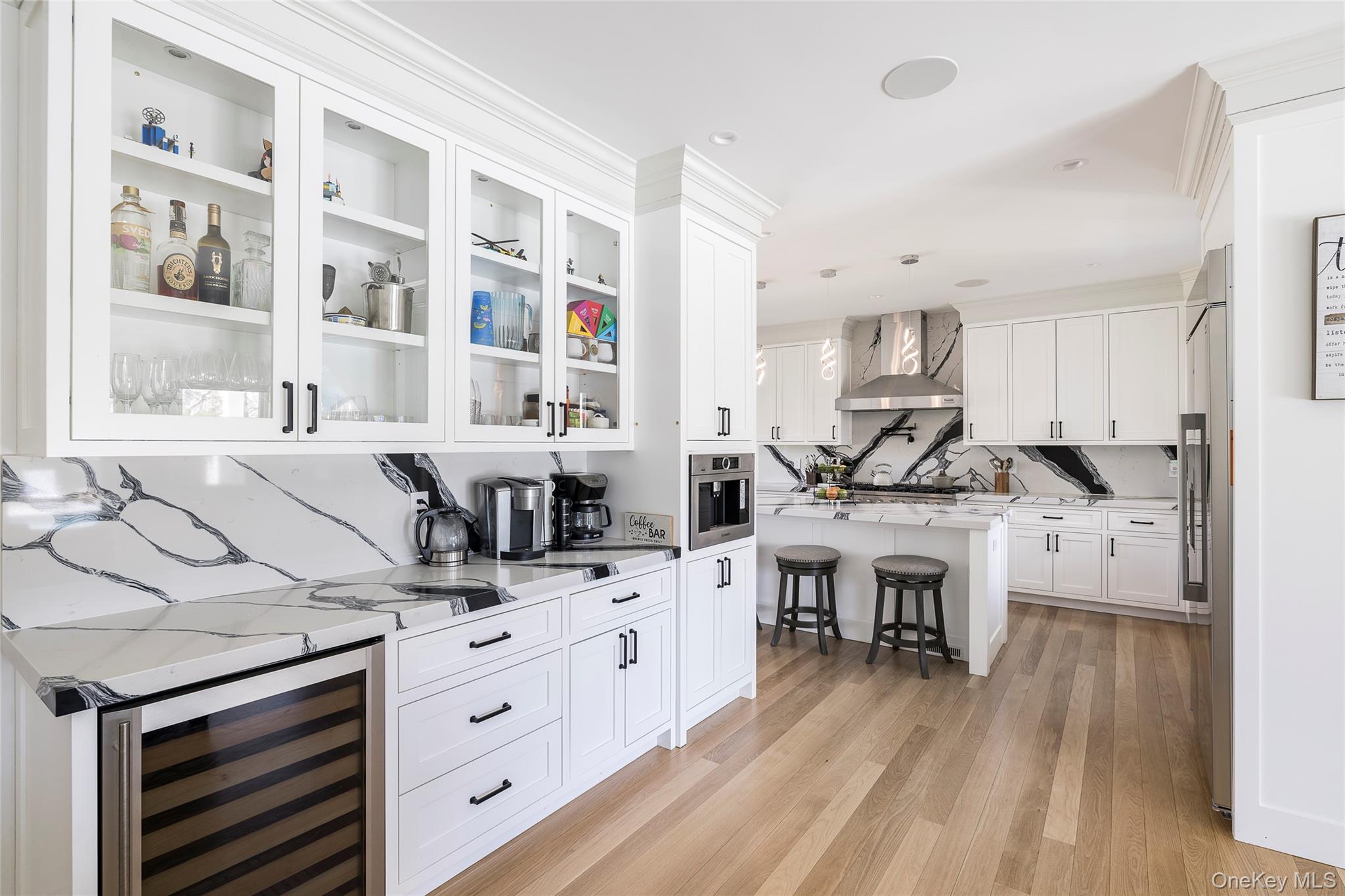 9 Jennifers Path Quiogue, NY 11978 - Photo 5 of 29 Bar with wall chimney range hood, appliances with stainless steel finishes, light wood finished floors, wine cooler, and pendant lighting