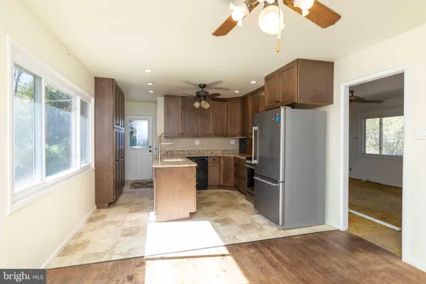 a kitchen with stainless steel appliances kitchen island granite countertop a refrigerator and a sink