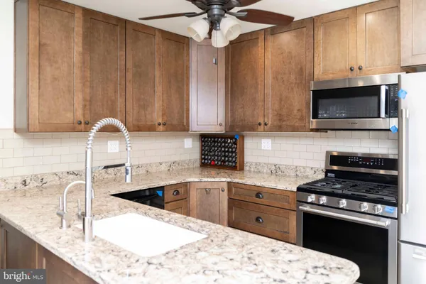 a kitchen with stainless steel appliances kitchen island granite countertop a sink a stove and a microwave