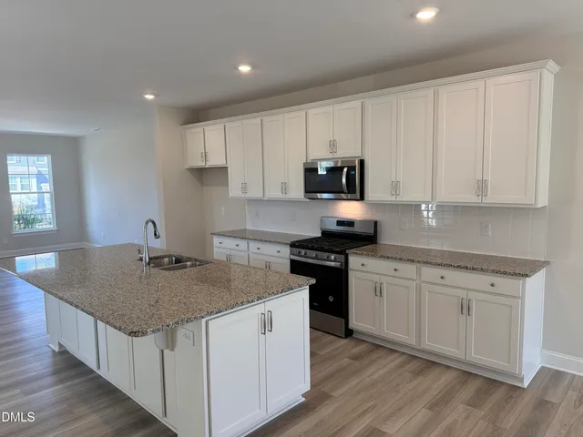 a kitchen with granite countertop white cabinets sink and stainless steel appliances