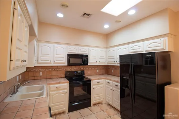 a kitchen with granite countertop a refrigerator and a stove top oven