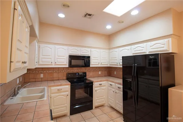 a kitchen with granite countertop a refrigerator and a stove top oven