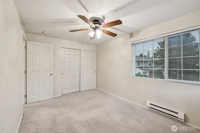 an empty room with windows and fan