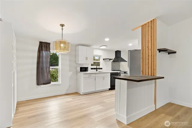 a kitchen with stainless steel appliances granite countertop a sink a stove and a wooden floor