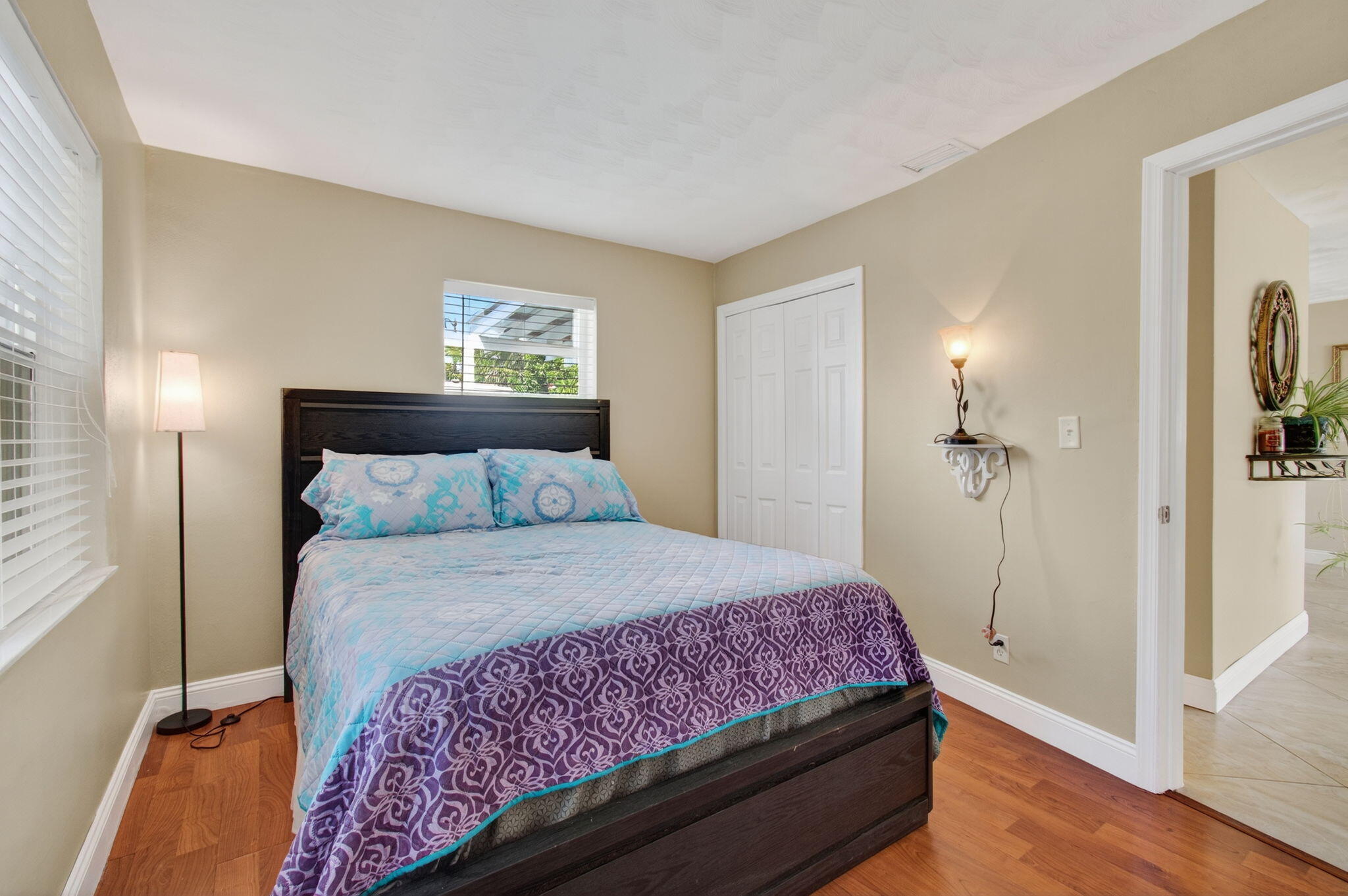 2841 Northeast 8th Terrace Pompano Beach, FL 33064 - Photo 38 of 65 a bedroom with a bed and a lamp with wooden floor