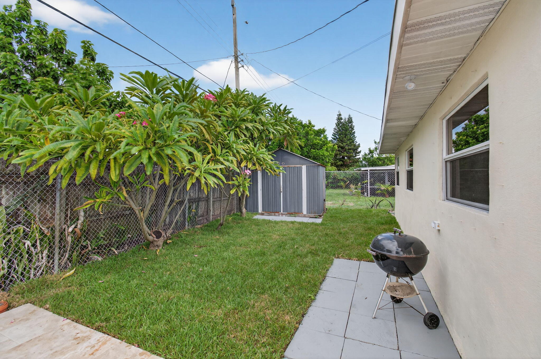 2841 Northeast 8th Terrace Pompano Beach, FL 33064 - Photo 51 of 65 a backyard of a house with table and chairs potted plants and a wooden fence