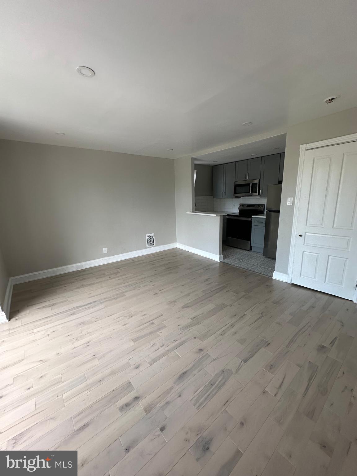 4710 Warrington Avenue, Unit 3 Philadelphia, PA 19143 - Photo 31 of 32 a view of empty room with wooden floor and kitchen
