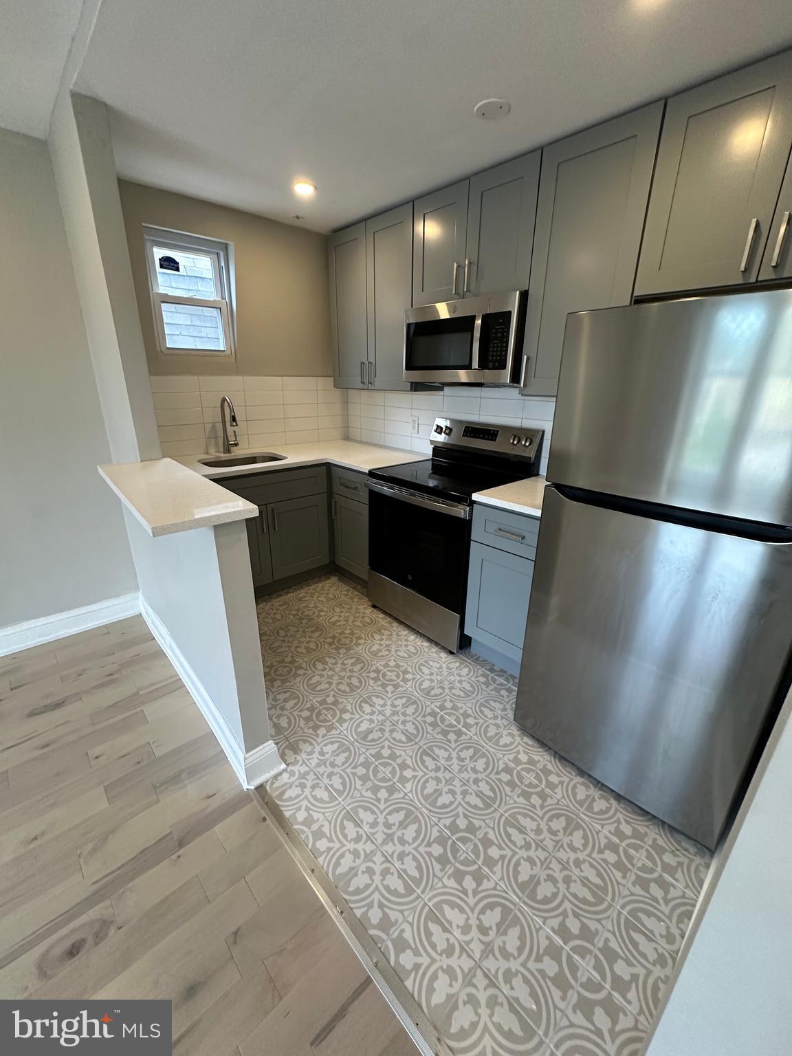 4710 Warrington Avenue, Unit 3 Philadelphia, PA 19143 - Photo 4 of 32 a kitchen with stainless steel appliances granite countertop a refrigerator sink and stove